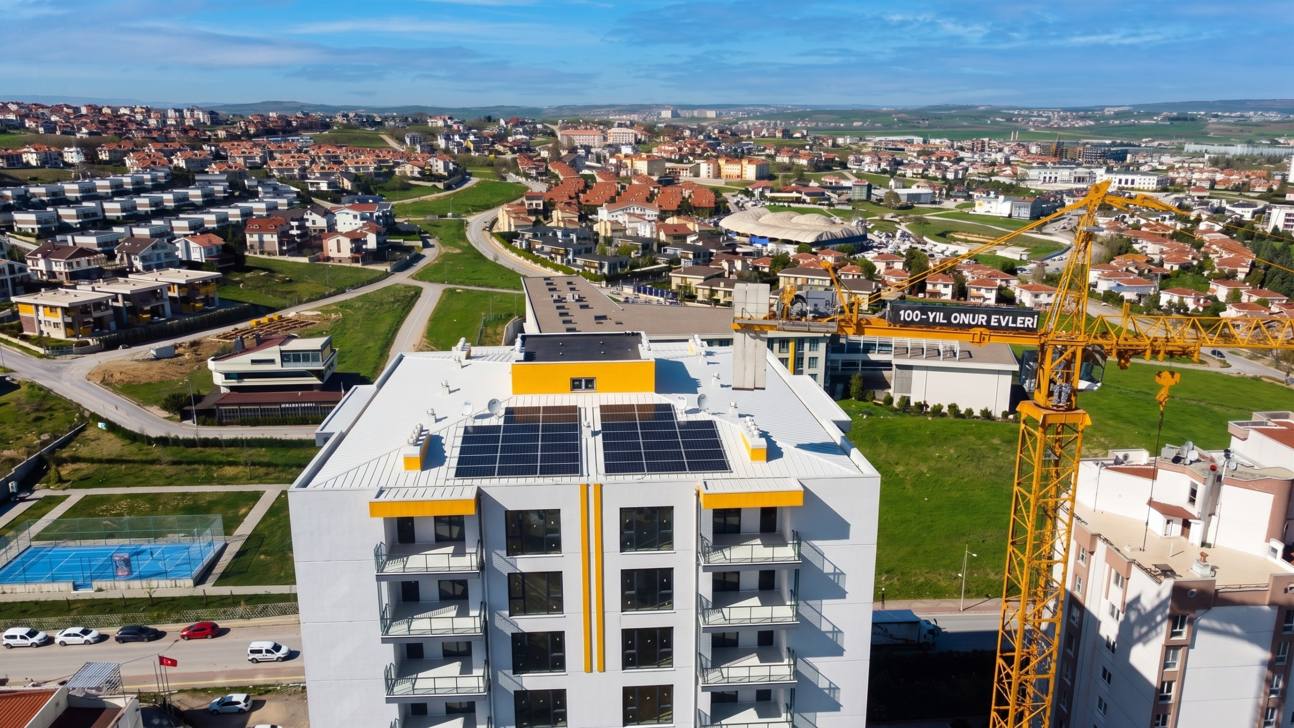 Bursa 100. Yıl Onur Evleri şantiyesinde, inşaat aşamasındayken apartman çatısına entegre edilen ortak alan güneş enerjisi (GES) panelleri ve kule vinç.