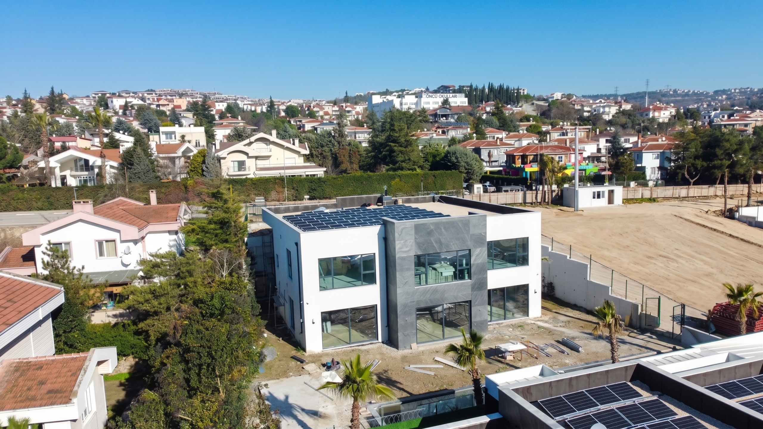Bursa Arkat Exclusive villa projesindeki modern evlerin düz çatılarına uygulanmış, bitişik nizam ve organize güneş paneli (GES) sistemlerinin kuşbakışı drone görüntüsü.
