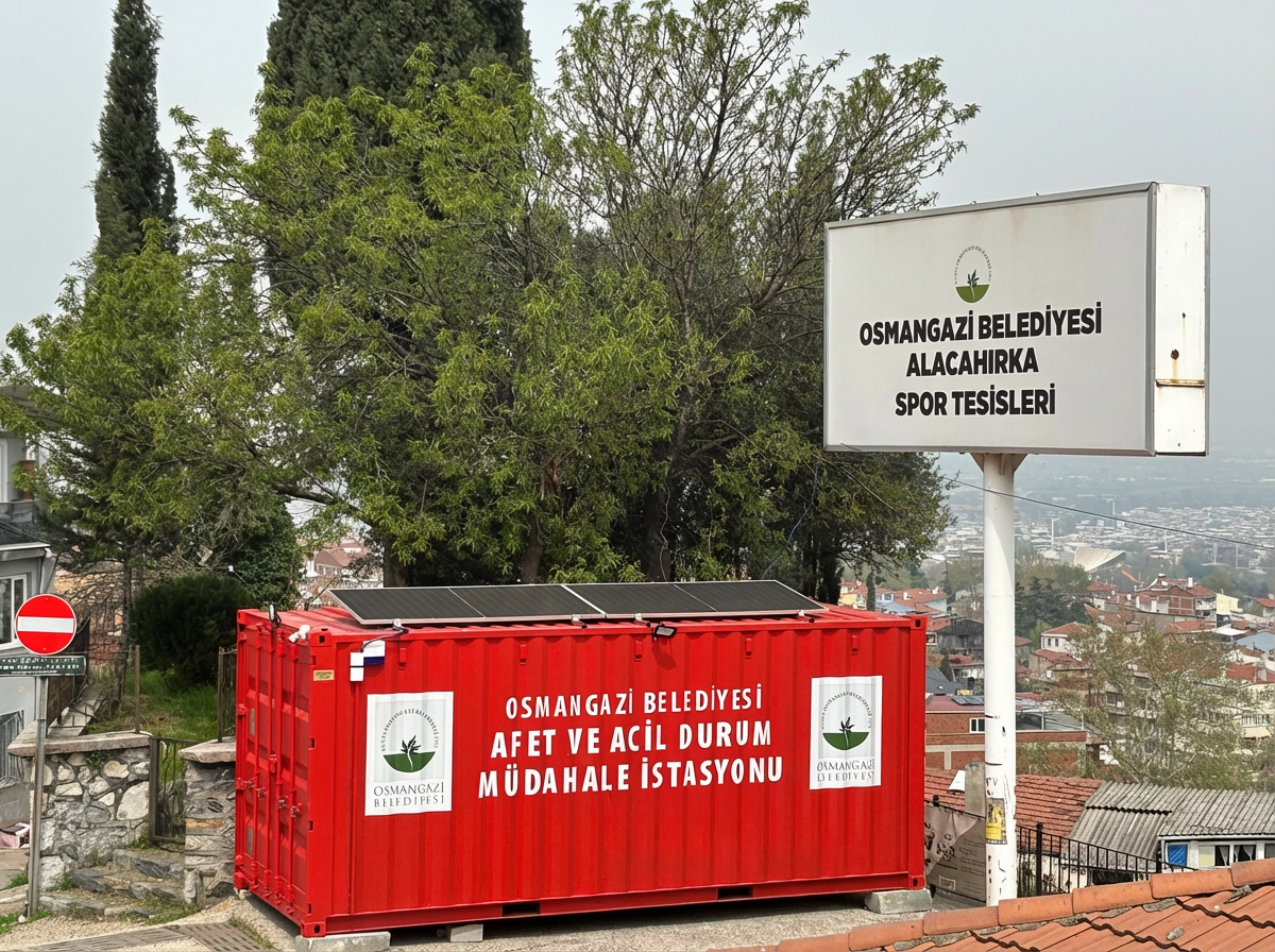 Bursa Osmangazi Alacahırka Spor Tesisleri girişine konumlandırılmış, çatısında off-grid güneş panelleri bulunan kırmızı renkli afet ve acil durum müdahale konteyneri.